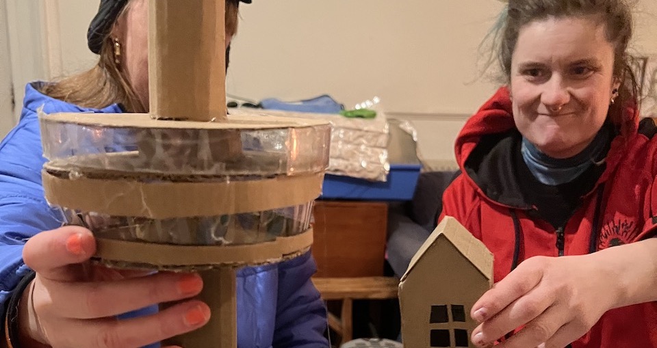 Two people holding cardboard miniature models of Liverpool buildings